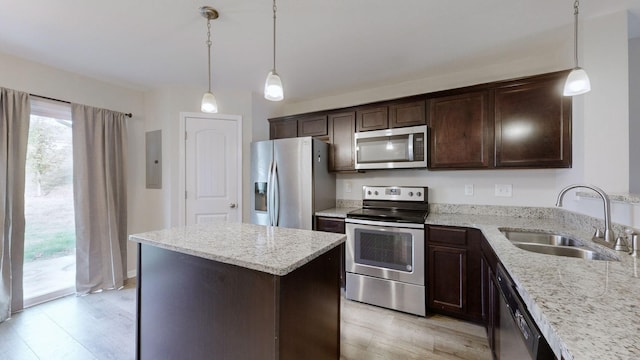 kitchen featuring sink, hanging light fixtures, a kitchen island, stainless steel appliances, and light stone countertops