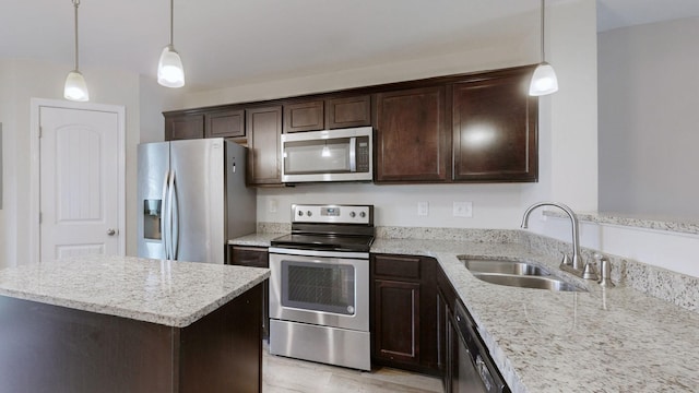 kitchen with sink, appliances with stainless steel finishes, hanging light fixtures, a center island, and light stone counters