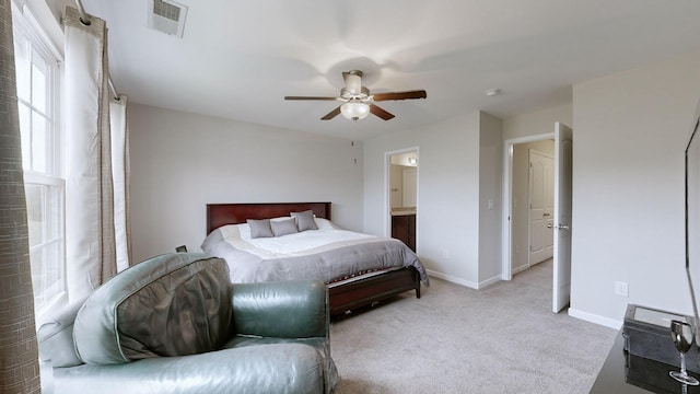 bedroom featuring light carpet, ensuite bath, and ceiling fan