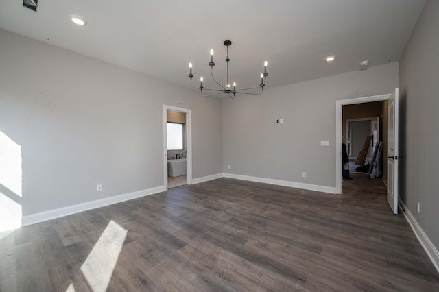 empty room with a notable chandelier and dark hardwood / wood-style floors