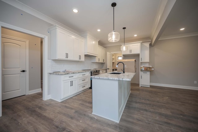 kitchen with pendant lighting, an island with sink, sink, and white cabinets