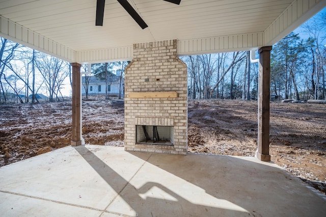 snow covered patio featuring an outdoor brick fireplace and ceiling fan