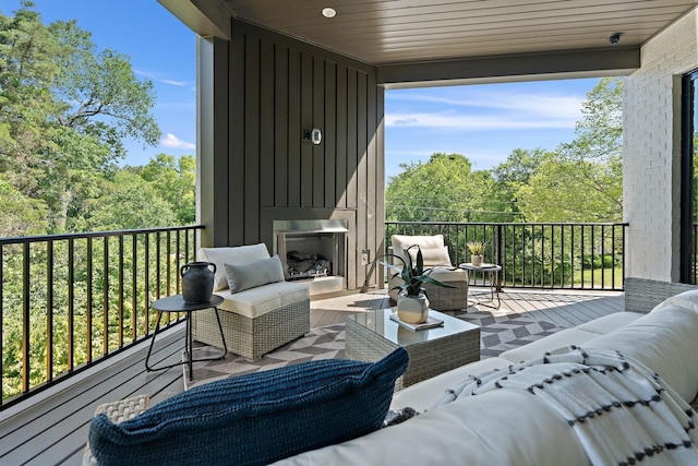 wooden terrace with an outdoor living space with a fireplace