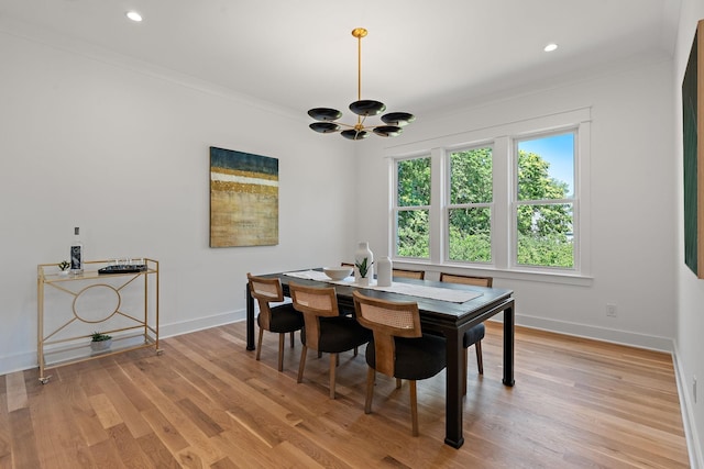 dining room with ornamental molding, light hardwood / wood-style flooring, and a notable chandelier