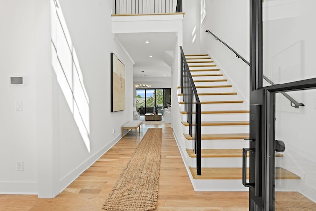 staircase featuring hardwood / wood-style flooring, a chandelier, and a high ceiling