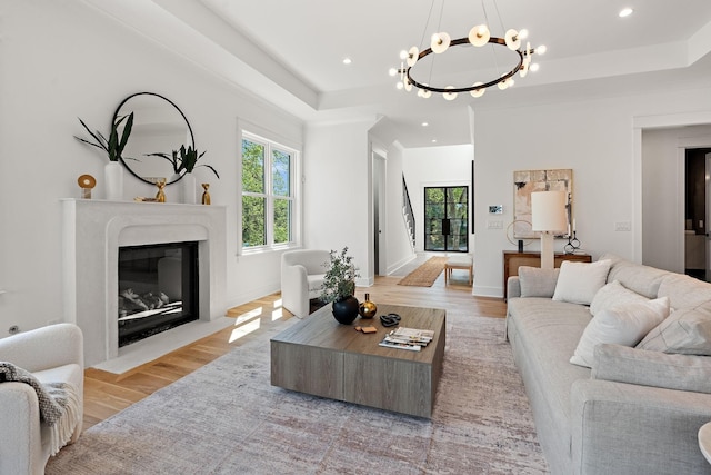 living room featuring a premium fireplace, a wealth of natural light, light hardwood / wood-style flooring, and a tray ceiling