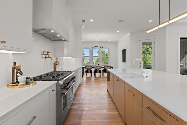 kitchen with pendant lighting, sink, high end stove, and white cabinets