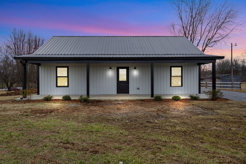 modern farmhouse style home with covered porch and a lawn