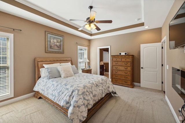 bedroom featuring ceiling fan, a tray ceiling, and light carpet