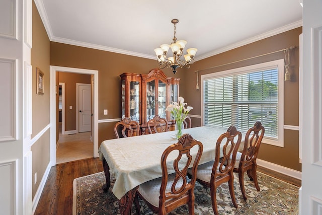 dining space with dark wood-type flooring, ornamental molding, and a chandelier