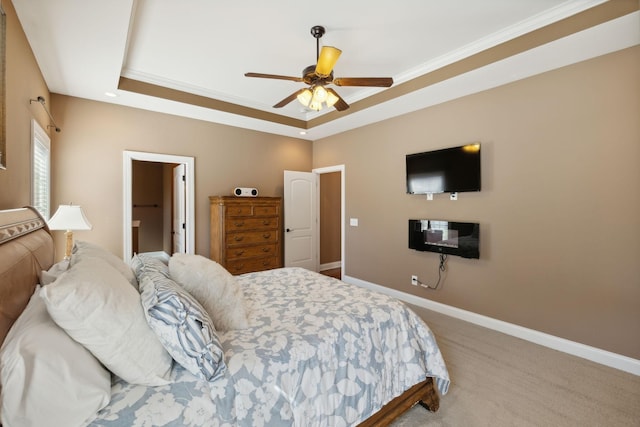 carpeted bedroom with a raised ceiling, crown molding, and ceiling fan