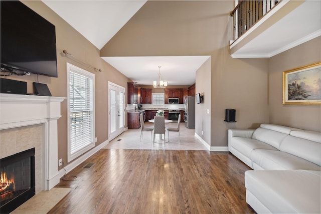 living room featuring a fireplace, high vaulted ceiling, and light wood-type flooring