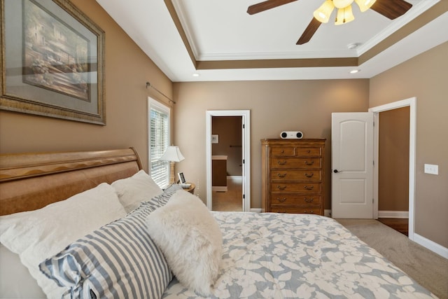 bedroom featuring connected bathroom, ornamental molding, light colored carpet, ceiling fan, and a raised ceiling