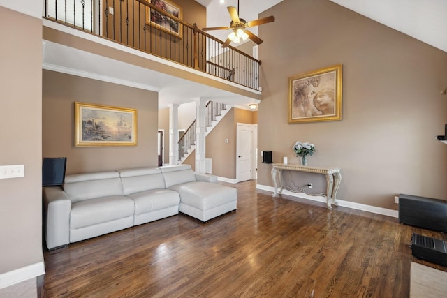 living room with ornamental molding, dark hardwood / wood-style floors, ceiling fan, and a towering ceiling