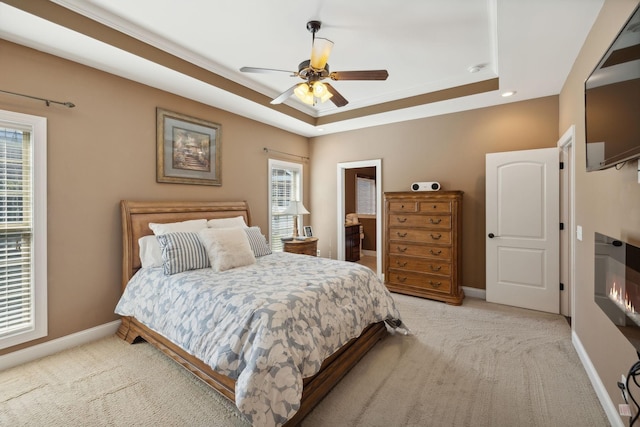 carpeted bedroom featuring a tray ceiling and ceiling fan