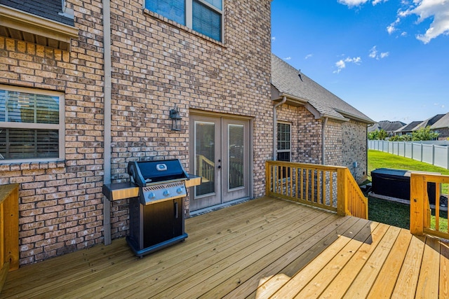 deck with a hot tub, grilling area, and french doors