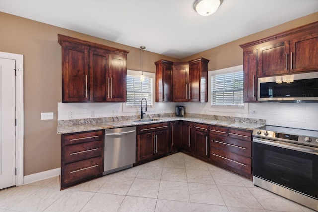 kitchen with sink, hanging light fixtures, stainless steel appliances, light stone counters, and a healthy amount of sunlight