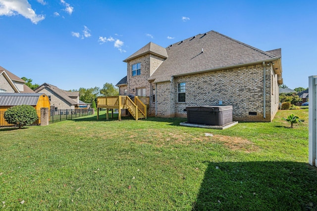 rear view of house with a shed, a hot tub, a deck, and a lawn