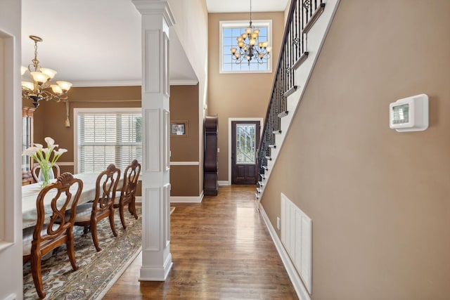 foyer with ornamental molding, decorative columns, dark hardwood / wood-style floors, and a chandelier