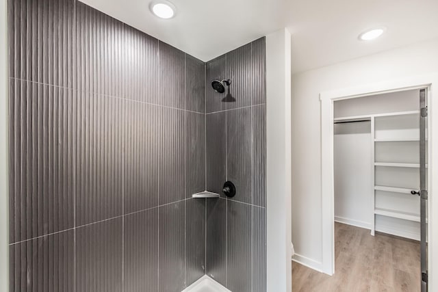 bathroom with hardwood / wood-style flooring and tiled shower