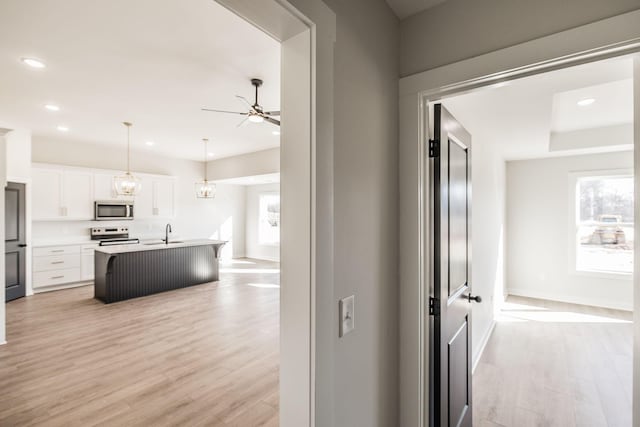 hallway with plenty of natural light, sink, an inviting chandelier, and light wood-type flooring