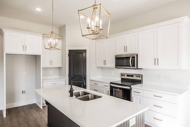 kitchen with stainless steel appliances, hanging light fixtures, sink, and a center island with sink