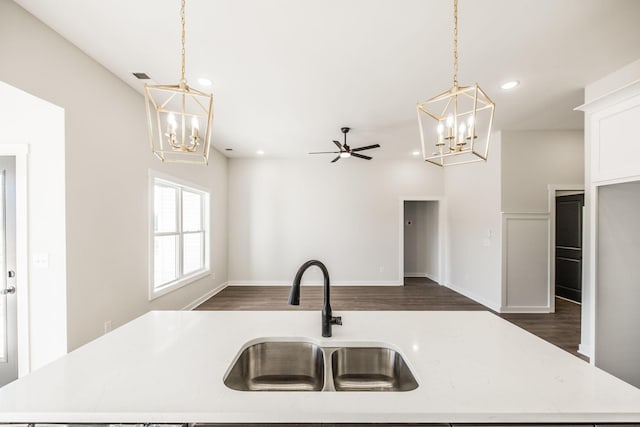 kitchen featuring a kitchen island with sink, sink, decorative light fixtures, and dark wood-type flooring