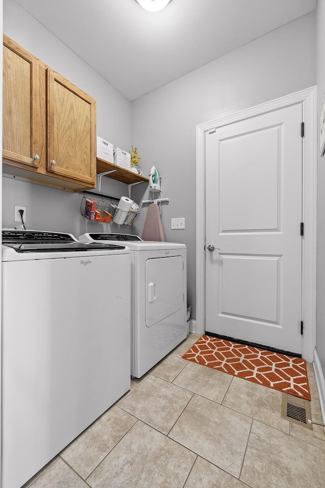 laundry area with cabinets, washing machine and dryer, and light tile patterned floors