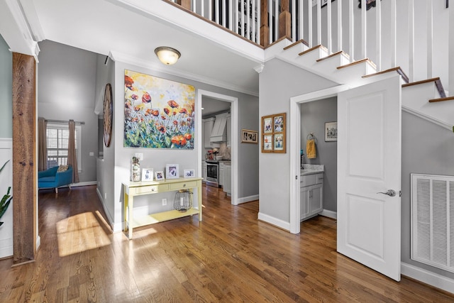 interior space featuring crown molding, hardwood / wood-style floors, and a high ceiling