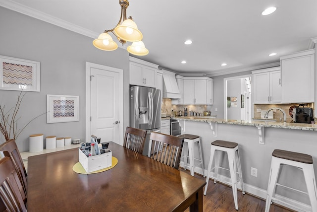 dining area with dark wood-type flooring, ornamental molding, and sink