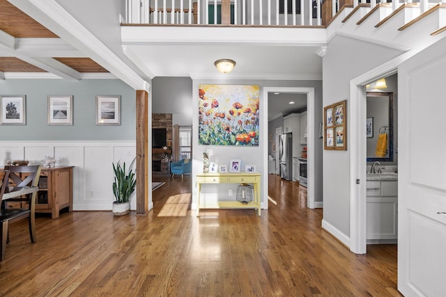 entryway featuring sink, hardwood / wood-style floors, a fireplace, ornamental molding, and beamed ceiling