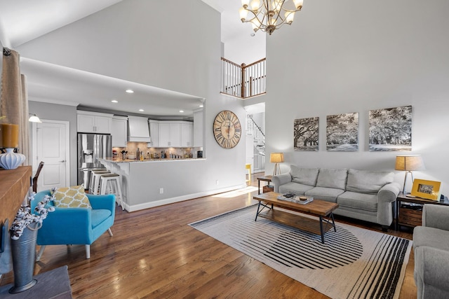 living room with dark wood-type flooring, ornamental molding, and a chandelier