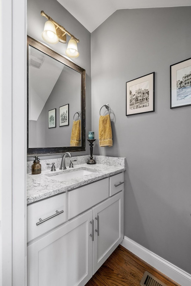 bathroom featuring lofted ceiling, vanity, and hardwood / wood-style floors