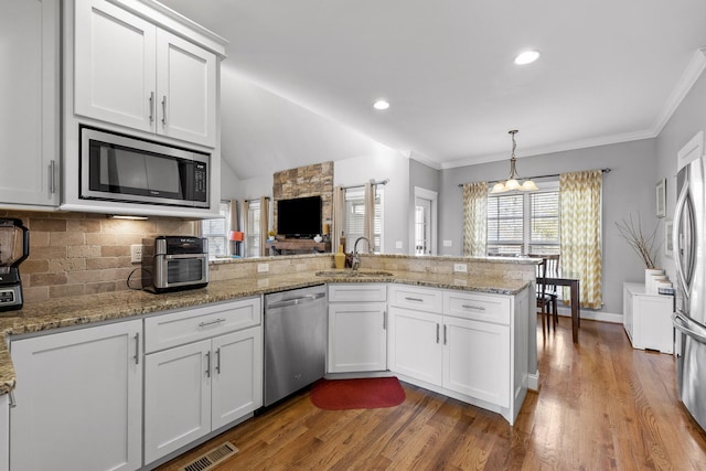 kitchen with white cabinetry, sink, hanging light fixtures, kitchen peninsula, and stainless steel appliances