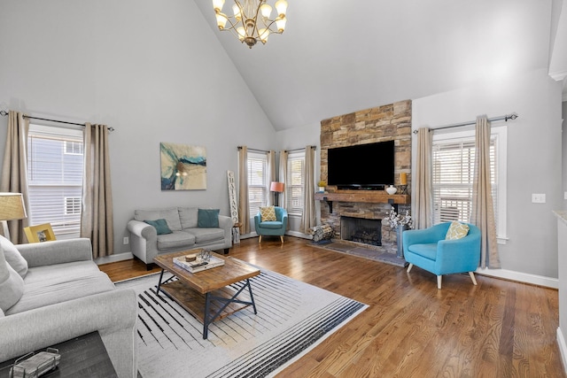 living room featuring an inviting chandelier, high vaulted ceiling, a stone fireplace, and hardwood / wood-style floors