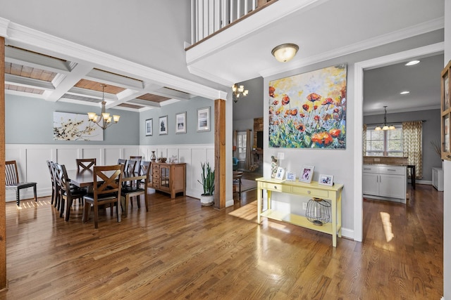 dining room featuring coffered ceiling, an inviting chandelier, ornamental molding, beamed ceiling, and hardwood / wood-style floors