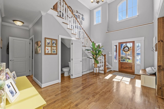 foyer entrance featuring hardwood / wood-style flooring, a towering ceiling, and ornamental molding