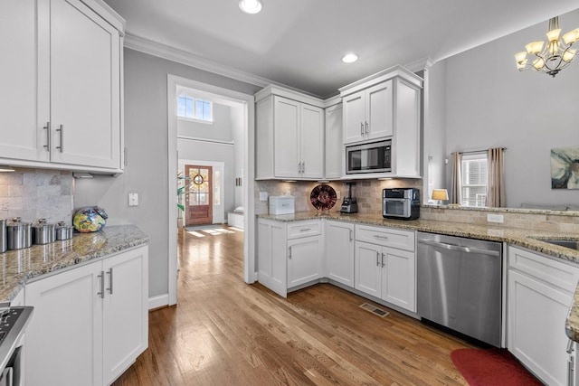 kitchen with light hardwood / wood-style flooring, white cabinetry, hanging light fixtures, an inviting chandelier, and stainless steel appliances