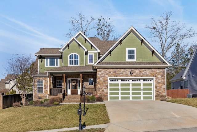 craftsman house with a garage, covered porch, a front yard, and central air condition unit