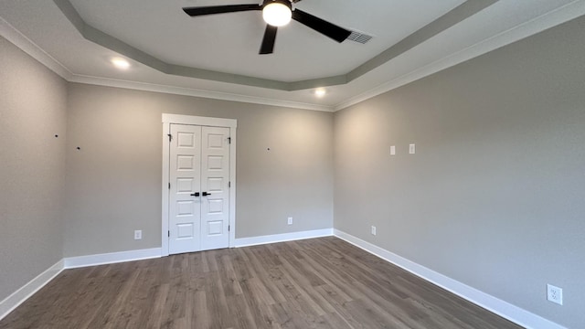 spare room featuring a tray ceiling, wood-type flooring, and ceiling fan