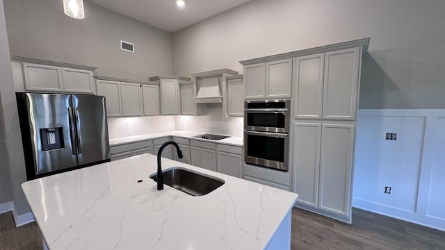 kitchen featuring sink, gray cabinets, premium range hood, appliances with stainless steel finishes, and light stone countertops