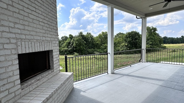 balcony with an outdoor brick fireplace and ceiling fan