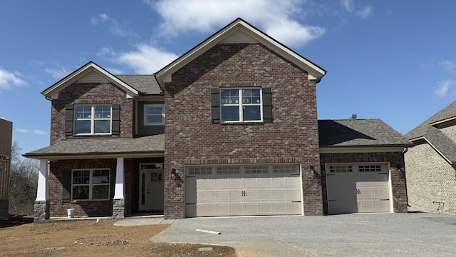 craftsman house featuring driveway, brick siding, and roof with shingles