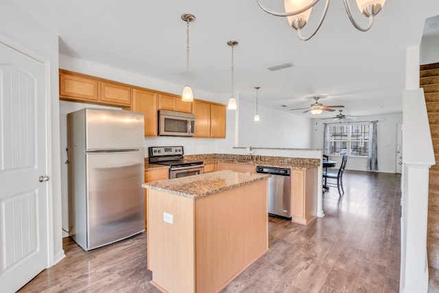 kitchen featuring hanging light fixtures, a center island, light hardwood / wood-style floors, stainless steel appliances, and light brown cabinets