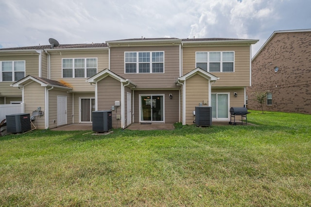 rear view of house featuring central AC unit and a lawn