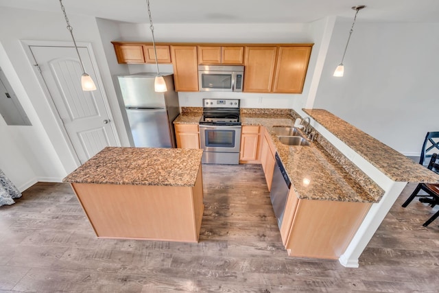 kitchen with a kitchen island, decorative light fixtures, sink, stainless steel appliances, and light hardwood / wood-style flooring