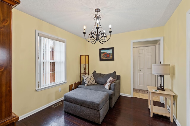 sitting room featuring a textured ceiling, dark hardwood / wood-style floors, and a chandelier