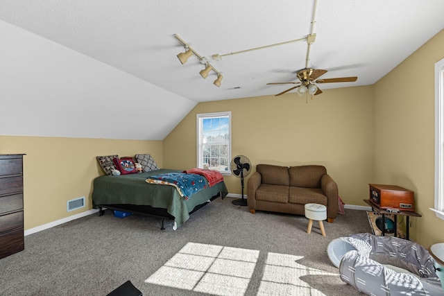 carpeted bedroom with vaulted ceiling, track lighting, ceiling fan, and a textured ceiling