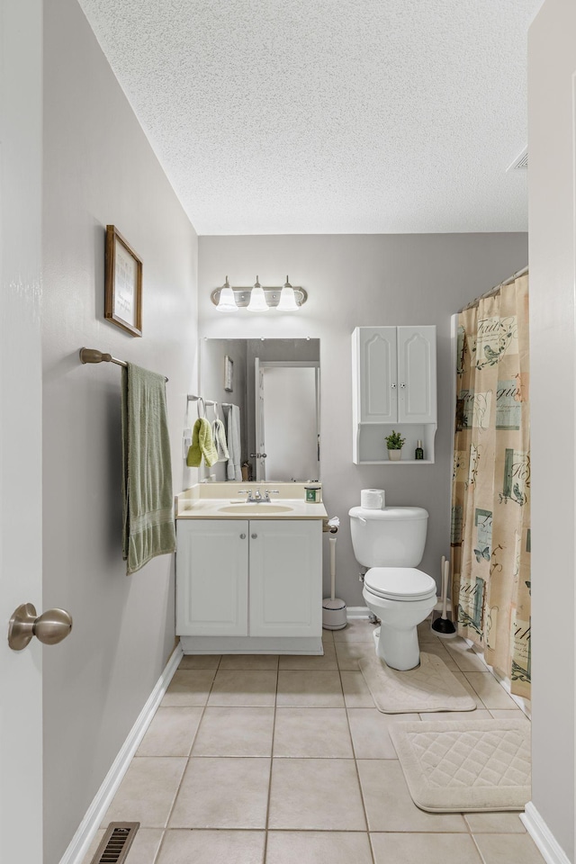 bathroom featuring tile patterned flooring, vanity, toilet, and a textured ceiling