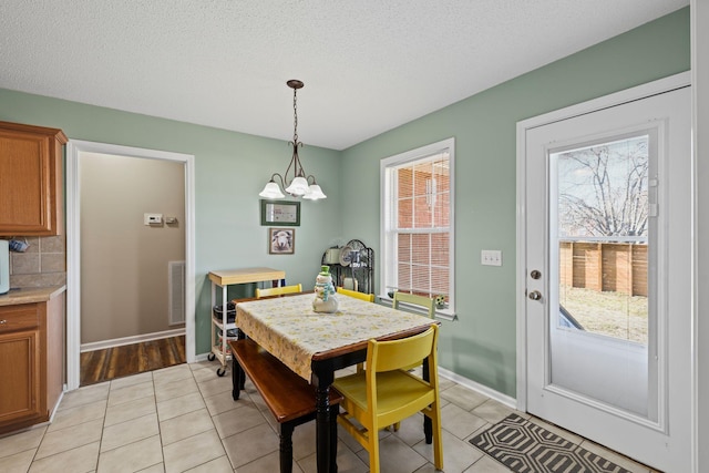 tiled dining area featuring a chandelier and a textured ceiling